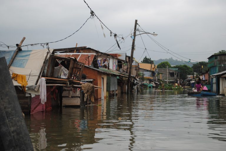 Flooded neighbourhood with houses standing in floodwater and a boat on the water in the Philippines