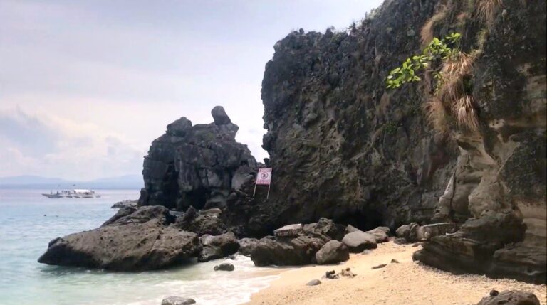 Dark rock formation and small beach on Apo Island