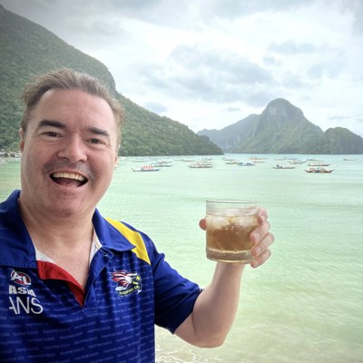 Dezza, an Australian who has lived in the Philippines since 2003, smiling on the beach at El Nido with a drink