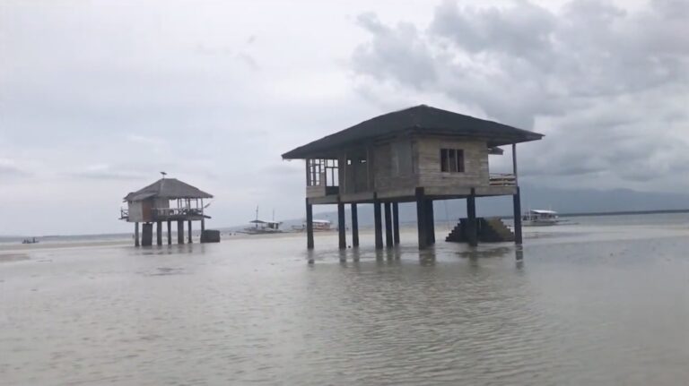 Stilt cottages standing on wet sand at low tide, Manjuyod Sandbar