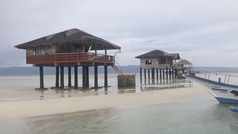 Stilt cottages and a boat as the tide drops at Manjuyod Sandbar
