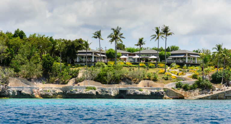 Palm trees and clifftop buildings above turquoise water on the Nasugbu coast, Batangas