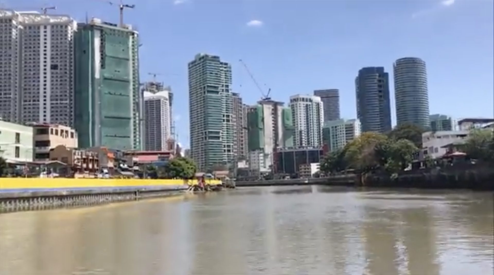 The Pasig River in Manila with city towers under a blue sky